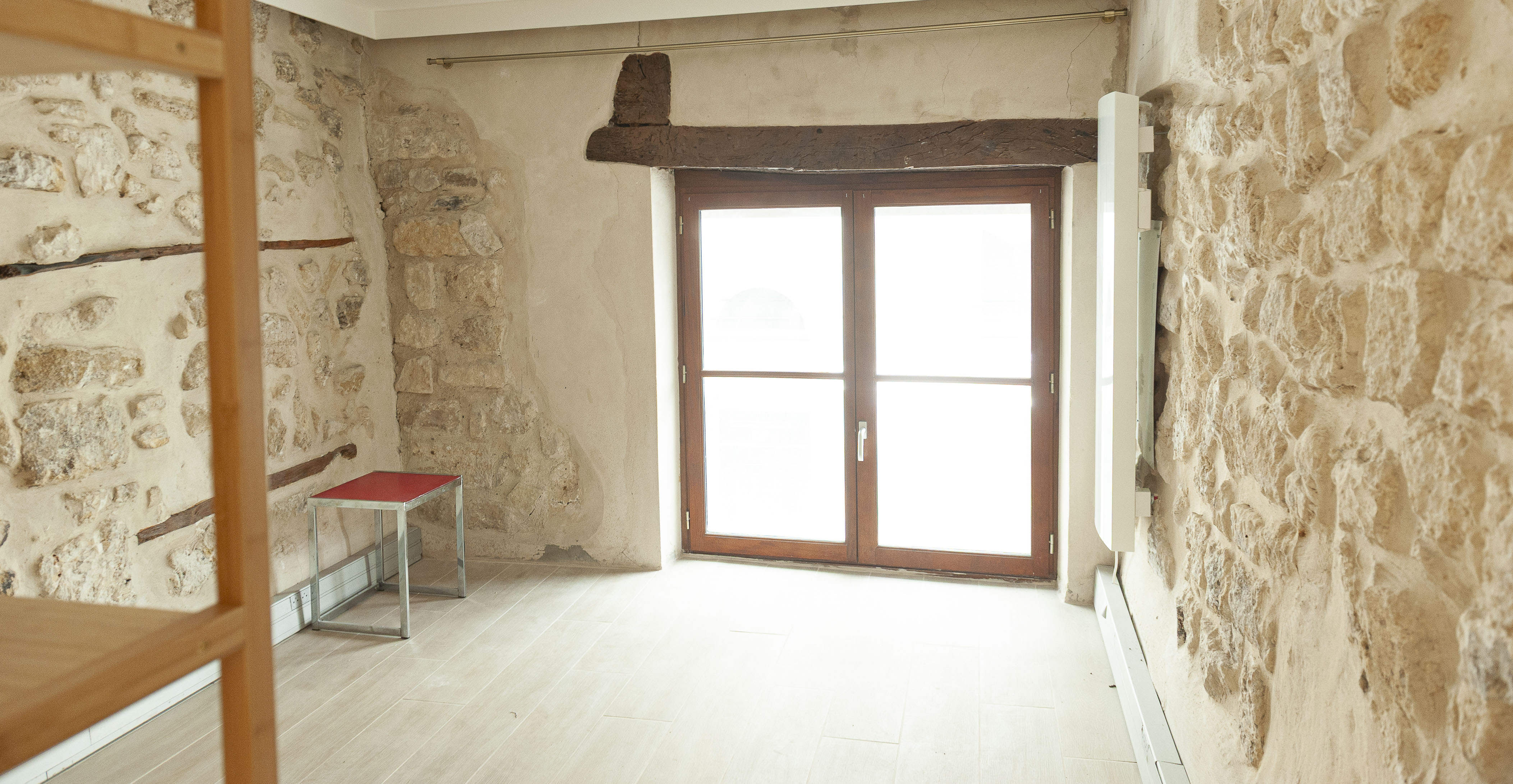 Chambre appartement de charme Paris 2e - murs pierres apparentes, grande fenêtre