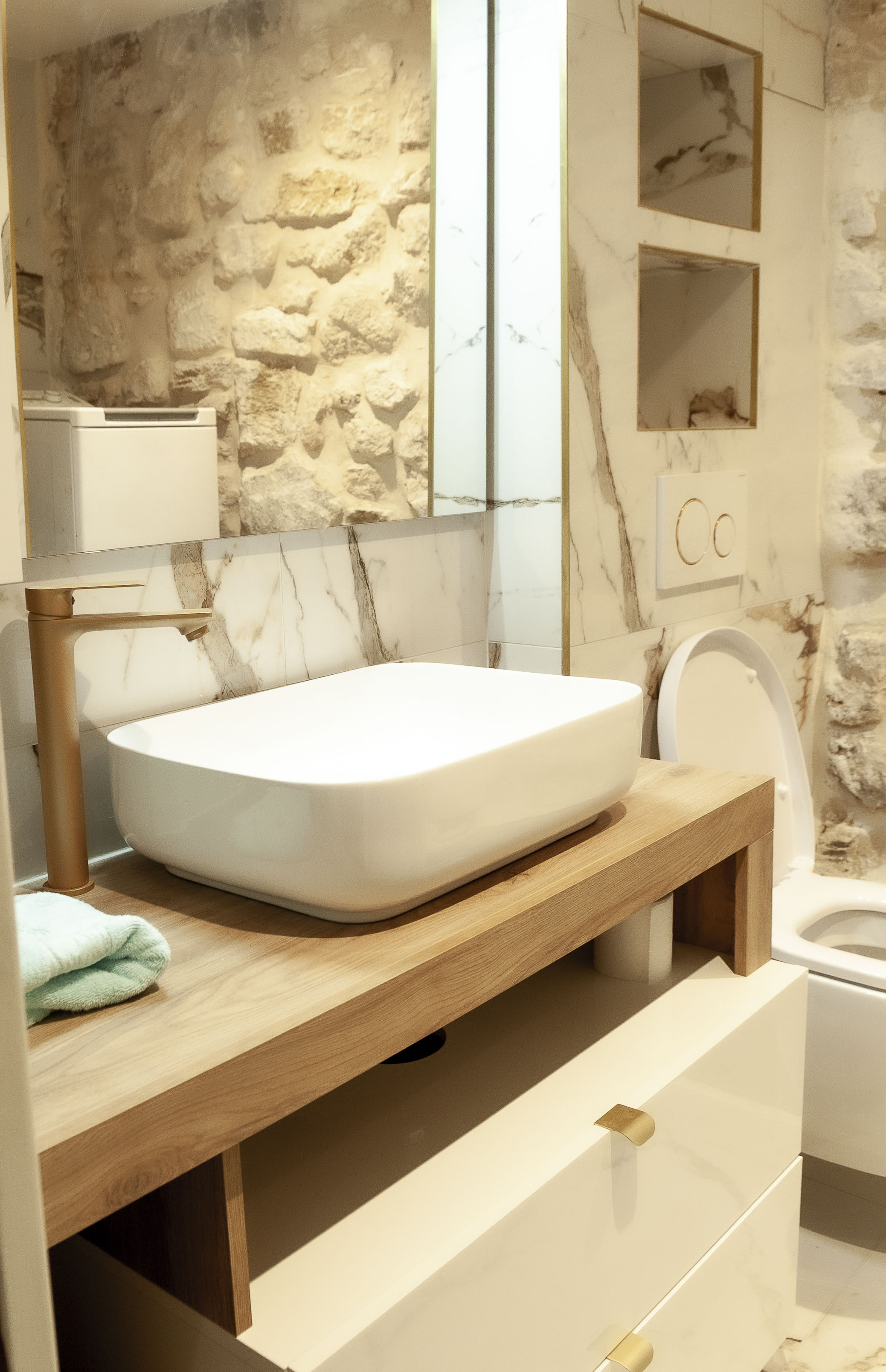 Salle de bain marbre blanc vasque à poser meuble bois robinetterie dorée Paris 2e